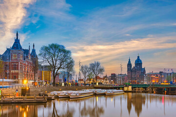 Fototapeta premium Amsterdam Netherlands, night city skyline at Amsterdam Central Station and Basilica of Saint Nicholas