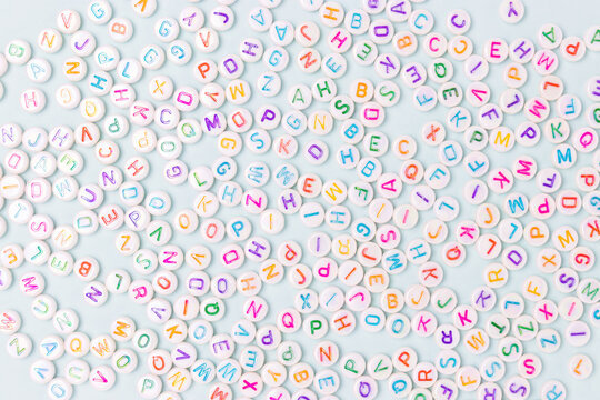 Beads with letters scattered on a blue pastel background.