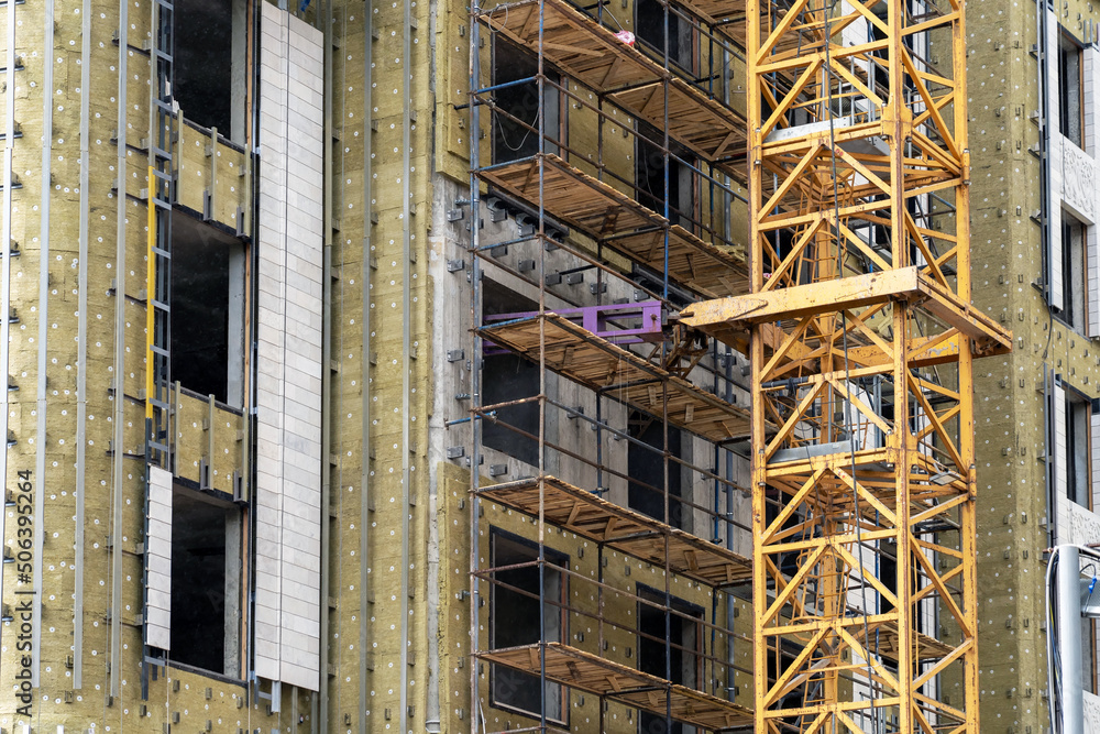 Poster installation of external wall thermal insulation with rock wool. frame part of metallic crane machin