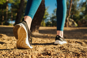 Young woman wearing blue yoga pants and black sneakers runner getting ready for start. Walking, outdoor sports, new day, sport and healthy life concept.