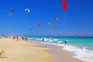 Tarifa, (Costa de la luz, Playa de Bolonia), Spanien - Wunderschöner Sandstrand am Atlantik, türkisfarbenes Wasser, Wellen, Kitesurfer, blauer Himmel, verschwommener afrikanischer Kontinent