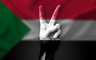 Hand making the V victory sign with flag of sudan