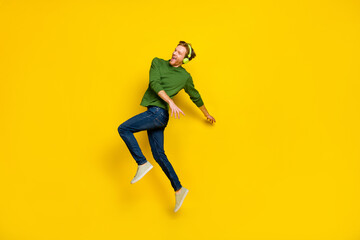 Fototapeta na wymiar Full length photo of pretty cool man wear pullover headphones dancing empty space isolated yellow color background