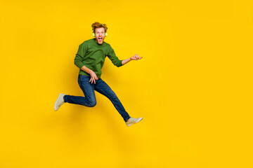 Fototapeta na wymiar Full length photo of excited funky man wear pullover headphones playing guitar empty space isolated yellow color background