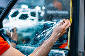 Professional worker installing ceramic film on car window