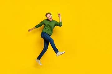 Fototapeta na wymiar Full length photo of dreamy funny guy dressed sweater earphones enjoying music dancing empty space isolated yellow color background