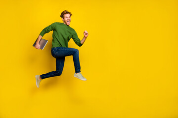 Fototapeta na wymiar Full length photo of excited pretty guy dressed sweater walking modern device empty space isolated yellow color background