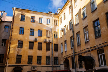 Saint Petersburg, Russia, 17 October 2021: Hight narrow courtyards called well in center, old architecture, Bottom up view, piece of sky is visible between profitable yellow houses, Dark inner