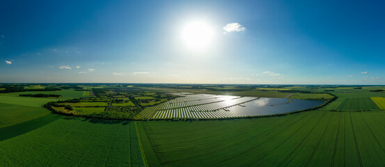 Panorama. Large solar power plant on a picturesque green field. Solar panels in aerial view. Power...