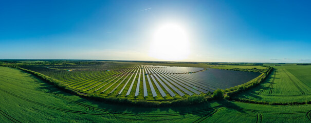 Panorama. Large solar power plant on a picturesque green field. Solar panels in aerial view. Power...