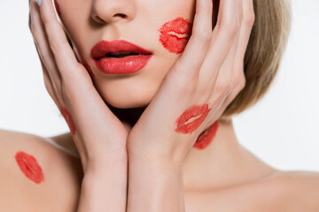 cropped view of young woman with red kiss prints on body touching face isolated on white