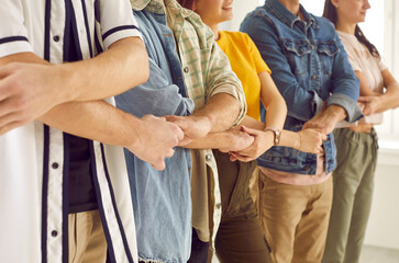 United we stand. Team of happy young people standing in row and holding hands. Cropped group shot of cheerful college or university friends standing in line and holding hands. Unity, support concepts - obrazy, fototapety, plakaty