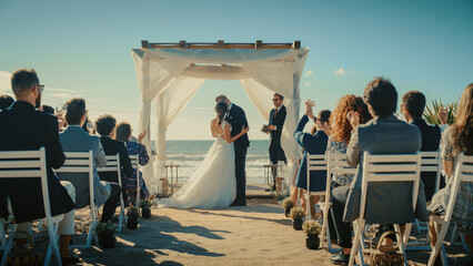 Beautiful Bride and Groom During an Outdoors Wedding Ceremony on a Beach Near the Ocean. Perfect Venue for Romantic Couple to Get Married, Kiss and for Friends with Multiethnic Cultures to Celebrate.