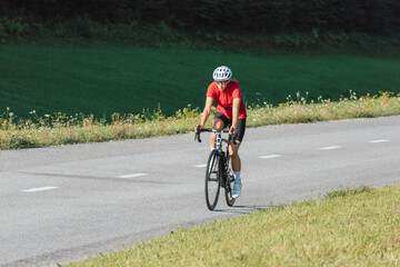 Obraz premium Caucasian girl cyclist with professional racing sports gear riding on an open road cycling route