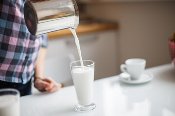 the girl is preparing morning coffee. the girl is preparing breakfast. the girl pours milk in a latte