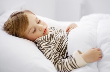 Sweet caucasian blonde adorable cute baby girl, toddler, sleeping in bed on white sheets, under warm blanket.Infant, child, kid having rest, nap,Quiet sleep, dream concept