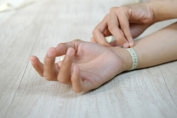 Close-up of woman's hand measuring wrist with measuring tape	