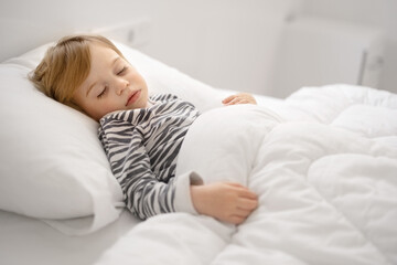 Sweet caucasian blonde adorable cute baby girl, toddler, sleeping in bed on white sheets, under warm blanket.Infant, child, kid having rest, nap,Quiet sleep, dream concept