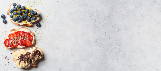 Banner of fruit vegetarian toasts for breakfast on gray background, copy space, top view. Bread...