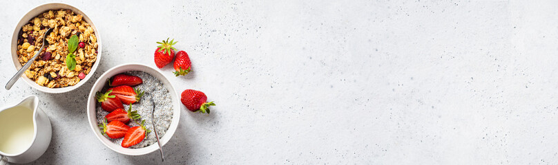 Breakfast banner. Granola bowl, milk and chia pudding with strawberries, gray background, top view, copy space.