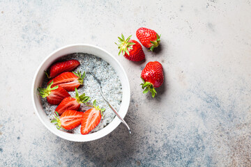 Chia pudding with strawberry in white bowl, dark background, top view.
