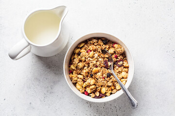 Homemade granola in white bowl, gray background, top view. Muesli bowl for healthy breakfast.