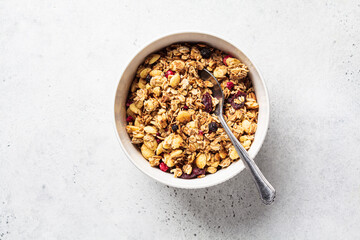 Homemade granola in white bowl, gray background, top view. Muesli bowl for healthy breakfast.