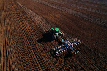 Tractor with cultivator plowing field. Tractor disk harrow on ploughing a soil. Planting in...