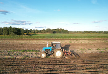 Tactor with disk harrow on plowing field. Cultivated land and soil tillage. Blue Tractor with disc...