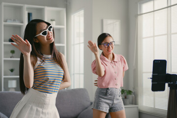 Asian young woman with her friend created her dancing video by smartphone camera together. To share video to Tiktok, social media application