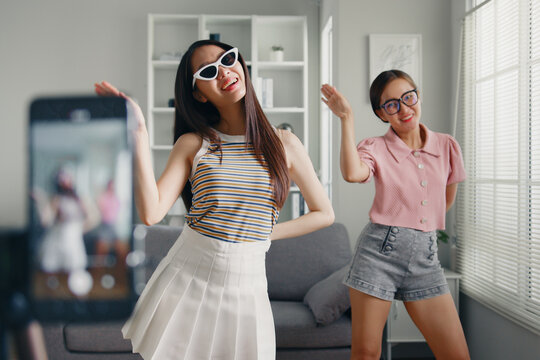 Asian young woman with her friend created her dancing video by smartphone camera together. To share video to Tiktok, social media application