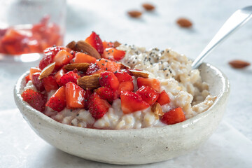 Oatmeal porridge with strawberries top view. Porridge oats in bowl. Healthy food breakfast