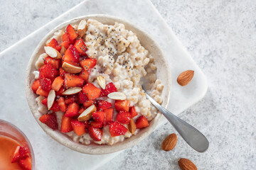 Oatmeal porridge with strawberries top view. Porridge oats in bowl. Healthy food breakfast