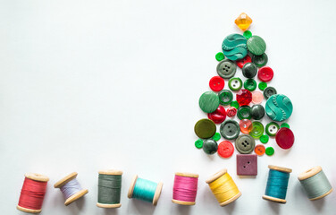 Tree made of buttons green, red color. Multicolored threads with wooden spools. White background, copy space. Creative Christmas concept