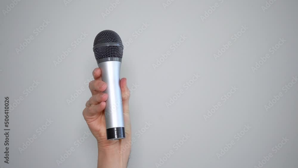 Poster man's hand holding a microphone and waving it back and forth in denial.