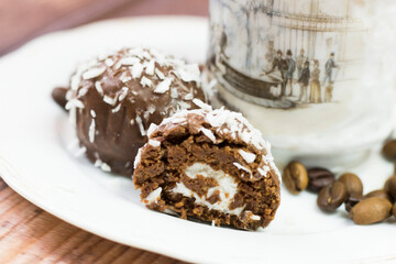 Chocolate round cakes with coconut and a cup of coffee on the piano