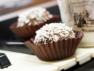 Chocolate round cakes with coconut on the piano