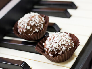 Chocolate round cakes with coconut on the piano