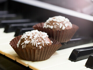 Chocolate round cakes with coconut on the piano