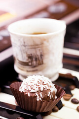 Chocolate round cakes with coconut and a cup of coffee on the piano