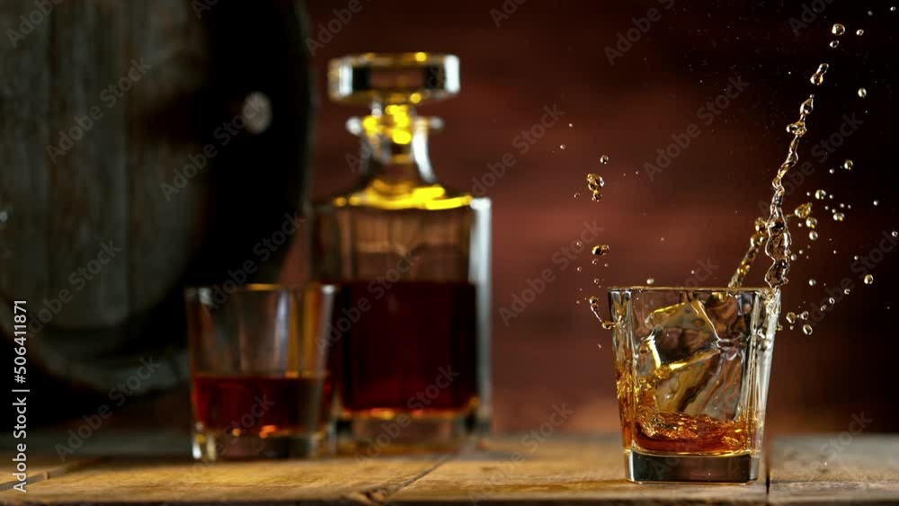 Poster super slow motion of falling ice cube into whiskey. speed ramp effect. filmed on high speed cinema c