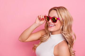 Portrait of satisfied glad person toothy smile hand touch sunglass isolated on pink color background