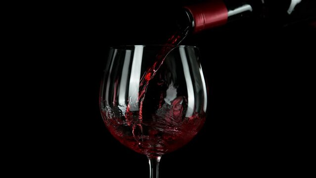 Super slow motion of pouring red wine in detail, isolated on black background. Speed ramp effect. Filmed on high speed cinema camera, 1000 fps