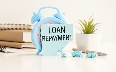 Alarm clock and a jar full of coins with text LOAN REPAYMENT