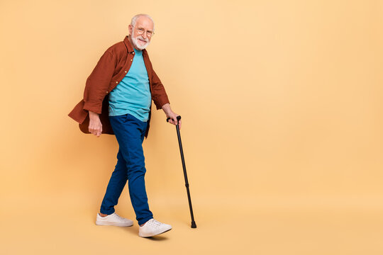 Full body photo of good mood pensioner man go on walk take care of his health isolated on beige color background