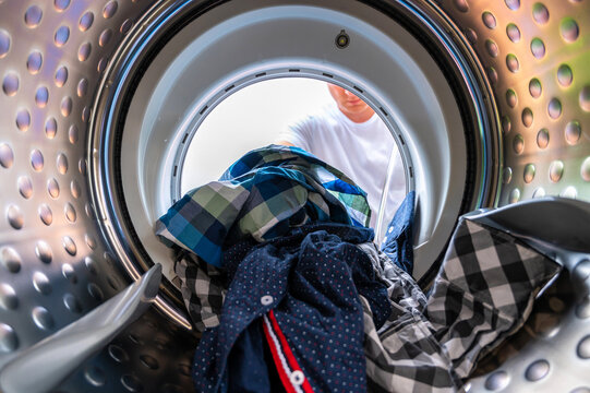 Blick aus einer Waschmaschine beim Beladen mit Schmutzwäsche