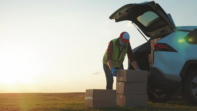 Delivery driver loading his van with boxes. Professional mover loads it cardboard boxes in car. Goods transportation and shipping.