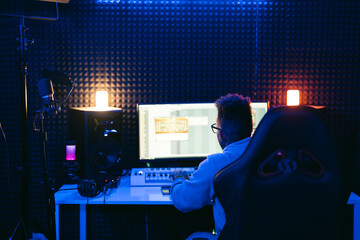 Producer, audio engineer uses a control panel and screen to record a track of a new album in a...