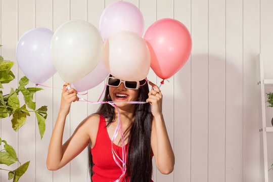 Portrait of cheerful young woman holding colorful balloons 