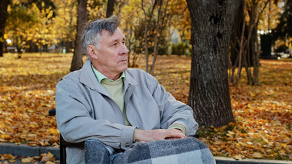 Mature outdoors upset senior retired caucasian man grandfather with disability sit alone at wheelchair depressed pensive old male person in older age has health problems feel lonely think of disease